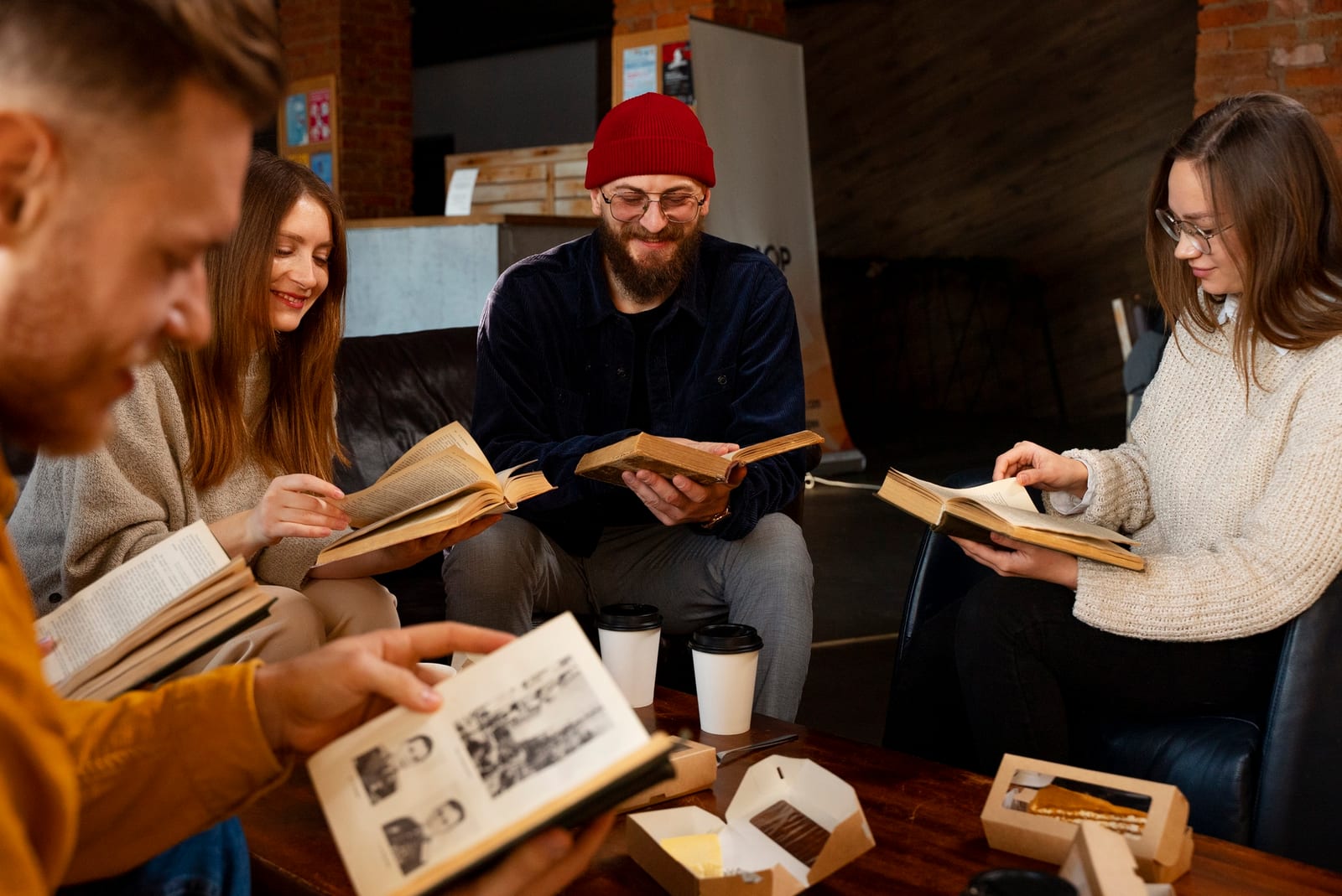 Grupo de quatro leitores reunidos em uma roda de leitura, cada um com um livro aberto nas mãos
